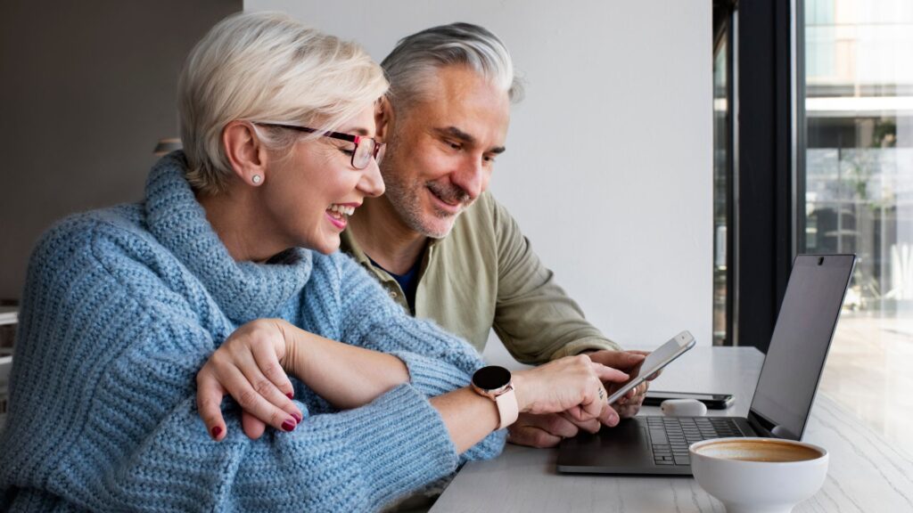 Dos adultos murando su celular y computador / Freepik