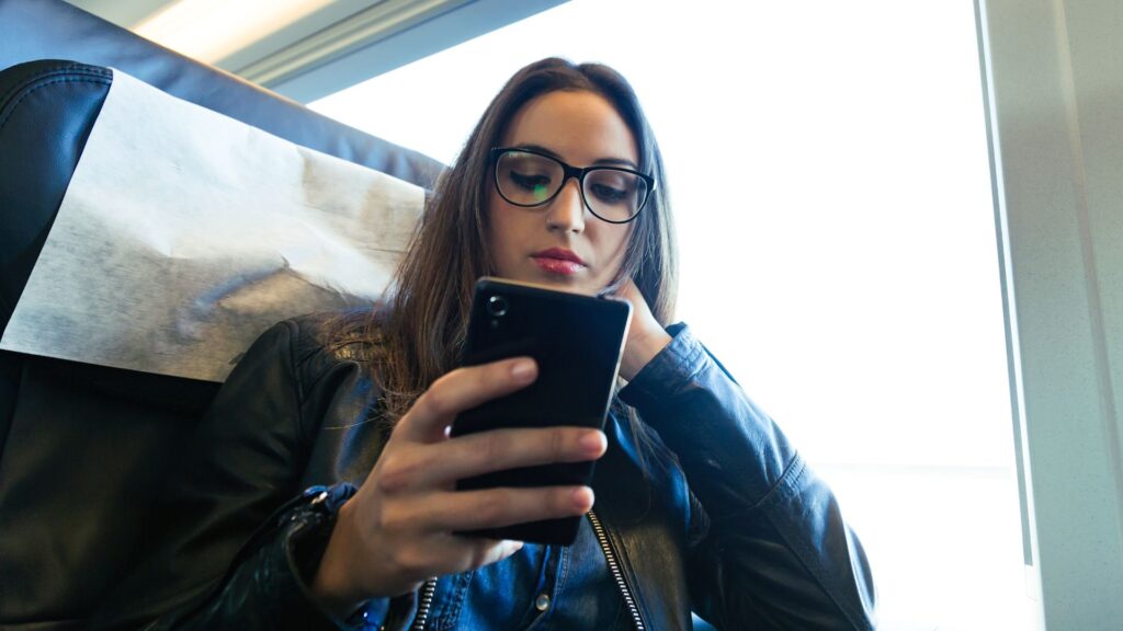Mujer en el avión mirando su celular / Freepik